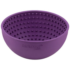 A dog licking food from the purple LICKIMAT Wobble dog lick mat.