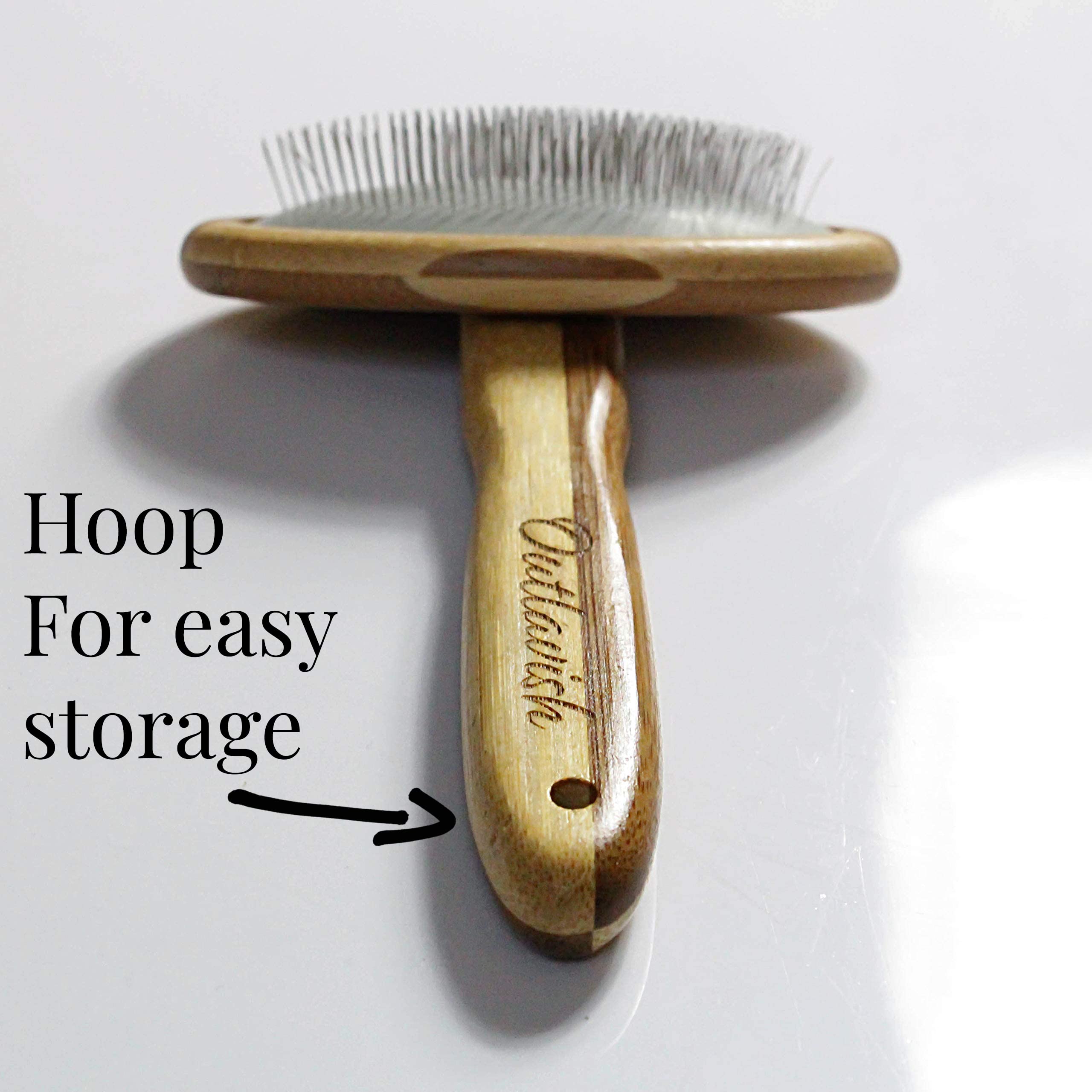 Outlavish wire carding brush smoothing a fluffy cat's coat.