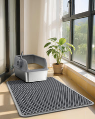 Powools cat litter mat with a heavy book placed on a crease to help flatten it.